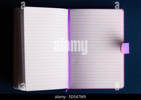 Overhead View of Open Lined Notebook with Blank Pages on Dark Blue Background Stock Photo