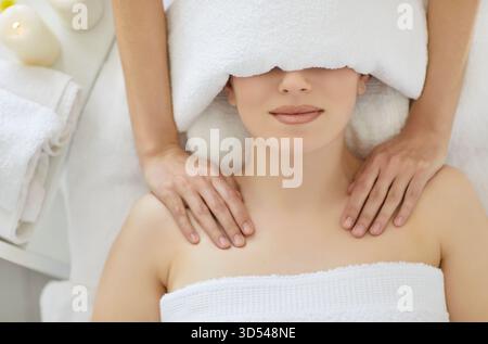 Relaxed woman wrapped in white towel enjoying massage in spa wellness center, top view Stock Photo