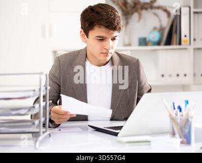 Male bookkeeper doing paperwork in workplace in office - checks accounting documents Stock Photo