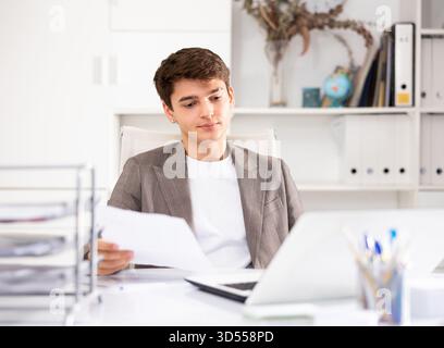 Male bookkeeper doing paperwork in workplace in office - checks accounting documents Stock Photo