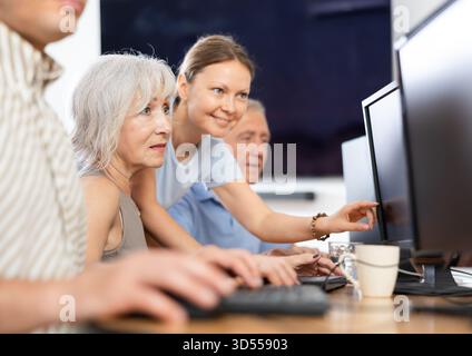 Young female mentor explaining something to elderly woman at computer lesson Stock Photo