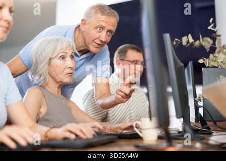 Older mentor explaining something to elderly woman during computer class Stock Photo