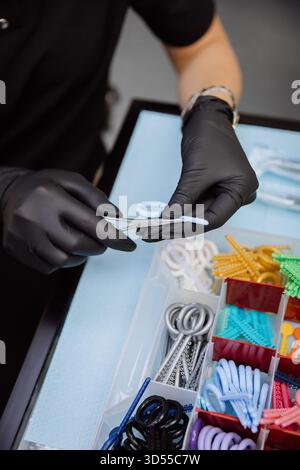 Orthodontic elastics and power chains selected with pliers in dental clinic, closeup Stock Photo