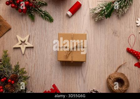 Wrapped gift box with twine on wooden table surrounded by festive elements, ideal for packaging concepts, small business branding and handmade product Stock Photo