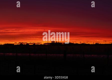 Fiery clouds filling the sky during a vibrant red sunset Stock Photo