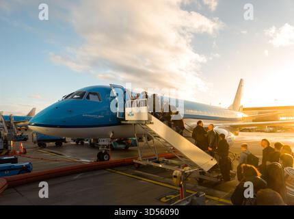 Passengers boarding KLM Cityhopper City Hopper using mobile airplane stairs Plane Embraer ERJ-175STD E175 on tarmac apron Amsterdam Schiphol Airport Stock Photo