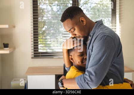 Father embracing son warmly at home, sharing tender moment together Stock Photo