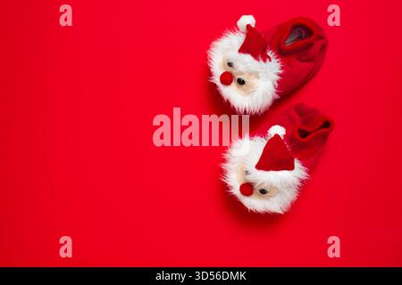 New year, Christmas slippers in form of santa claus with white soft fur on red background with place for text. Funny, cozy, fluffy children shoes Stock Photo