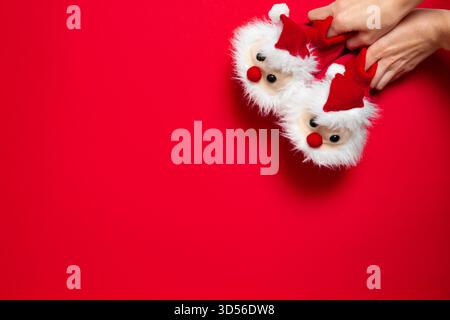 New year, Christmas slippers in form of santa claus with white soft fur on red background with place for text. Funny, warm, cozy, fluffy children Stock Photo