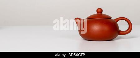 Chinese teapot. Red clay ceramic pot with lid and handle, traditional Asian design for serving hot tea, elegant vintage kitchenware, miniature breakfa Stock Photo