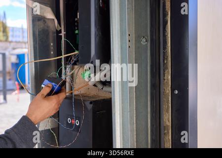 A technician is repairing an advanced automated door system with electrical tools Stock Photo