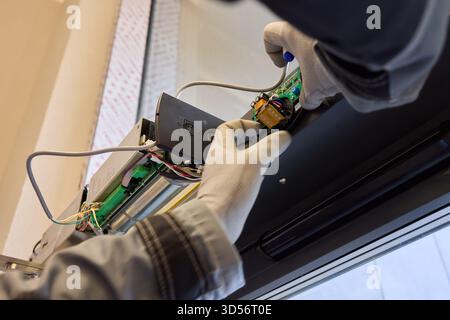 A technician is repairing an advanced automated door system with electrical tools Stock Photo