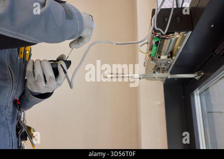 A technician is repairing an advanced automated door system with electrical tools Stock Photo