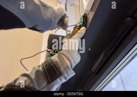A technician is repairing an advanced automated door system with electrical tools Stock Photo