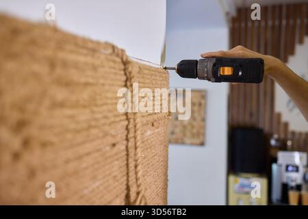 A skilled handyman is using a powered drill on a textured wall to enhance home improvement Stock Photo