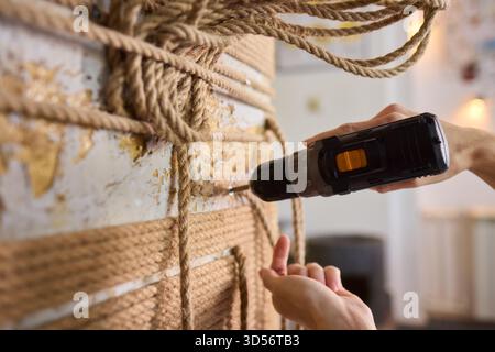 A skilled handyman is using a powered drill on a textured wall to enhance home improvement Stock Photo