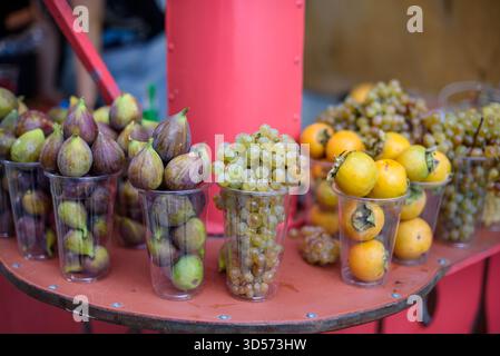 Assorted fruits in plastic cups on a red table. Stock Photo