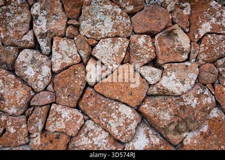 A wall made of rocks with a white substance on it. The wall is made of many different sized rocks Stock Photo