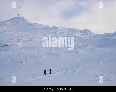 Ski-touring - two skiers in colorful jackets climb to the top of a mountain in the Narvikfjellet ski resort in Narvik. Lapland, Norway, Northern Europ Stock Photo