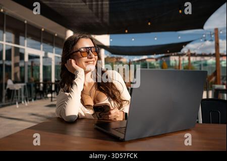 Woman using smartphone and laptop outdoors Stock Photo