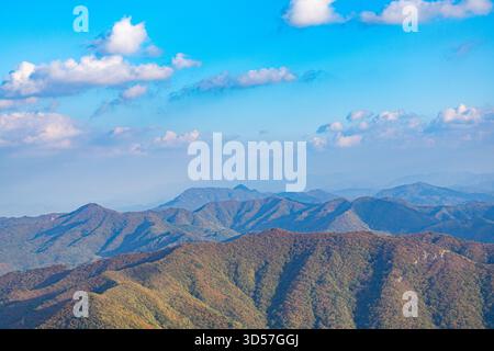 A peaceful panoramic view of layered mountain ridges with soft autumn tones under a bright blue sky at Stock Photo