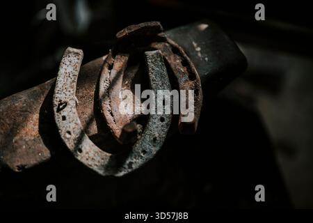 Rusty horseshoes resting on a blacksmith's anvil Stock Photo