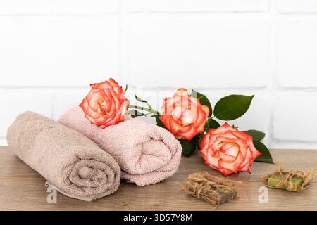 Spa composition with soft terry towels, red rose flowers and soap on the wooden floor. Stock Photo