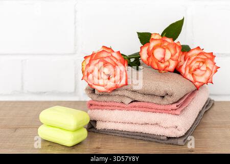 Spa composition with soft terry towels, red rose flowers and soap on the wooden floor. Stock Photo