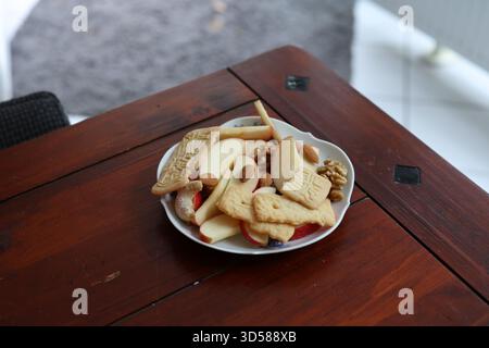 Plate with apple slices, nuts and cookies on a rustic wooden table. Stock Photo