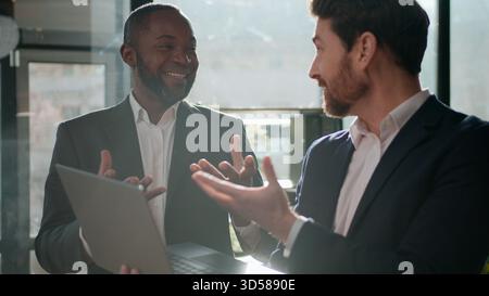 Two multiracial business men team with laptop partnership businessmen working together in office Caucasian man talking to African American male Stock Photo