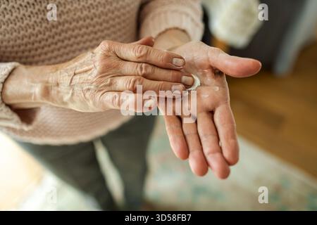 Senior woman applying moisturizer to her hands, close-up Stock Photo