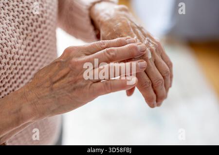 Senior woman applying moisturizer to her hands, close-up Stock Photo