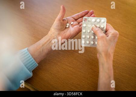 Senior woman taking her medication at home, close-up of hands Stock Photo