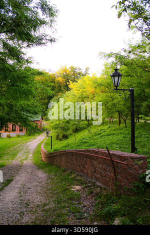 A green path in the village next to a low stone wall, mystical vibe the park of Feofania Kyiv Stock Photo