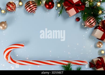 Festive Christmas scene with red and white candy cane, gifts, ornaments, and pine branches on blue. 3d rendering Stock Photo