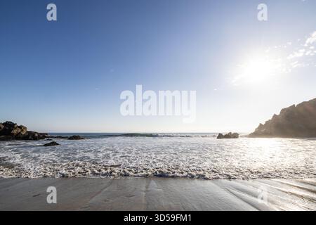 Sunlit waves rolling onto the sandy shoreline at Pfeiffer Beach, Big Sur, California. Stock Photo