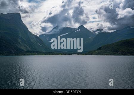Eresfjord village nestled between towering mountains with the fjord under the dramatic sky and rugged peaks, natural beauty of Møre Og Romsdal, Norway Stock Photo