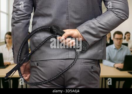 A stylish man in a gray suit holds a black whip behind his back, suggesting control, despotism, and a violently coercive form of leadership. Stock Photo
