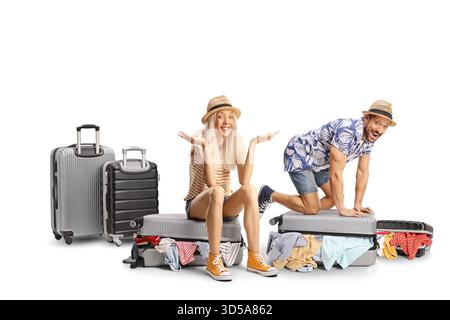 Funny young couple trying to close overpacked suitcases isolated on white background Stock Photo