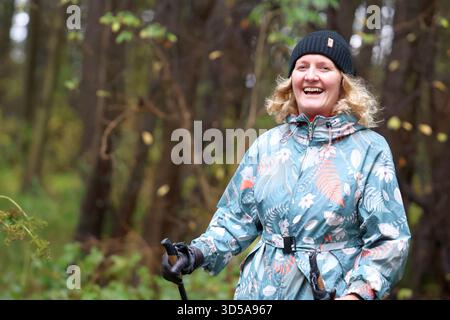 Happy Woman Nordic Walking in a Lush autumn Forest Stock Photo