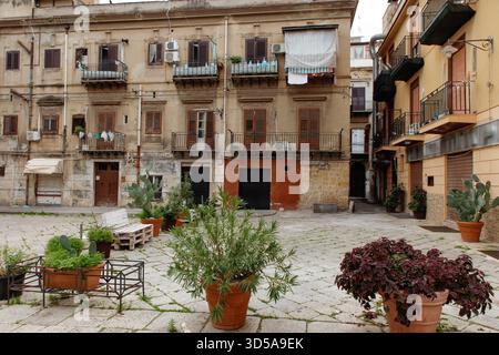 A sunlit courtyard framed by aged buildings, balconies with laundry, and thriving potted plants. This urban scene evokes charm, daily life, and a rust Stock Photo