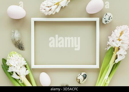 Subtle Easter mockup with white frame, easter eggs and flowers on a pastel colored background Stock Photo