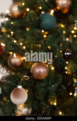 Close-up of Christmas tree branches decorated with glittering baubles and warm festive lights Stock Photo
