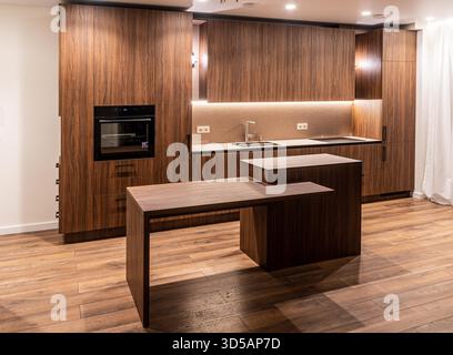 Modern kitchen interior with wooden cabinets, integrated appliances, and warm ambient lighting highlighting a minimalist design Stock Photo