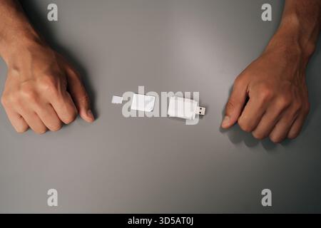 Top view of electronic technician comparing memory card sizes, from smallest to largest, including micro sd, sd card and usb drive Stock Photo