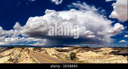 Utah State Route 12 winds over The Hogback in Grand Staircase-Escalante National Monument. A large, dramatic storm cloud with rain (virga) hangs over the vast slickrock landscape Stock Photo