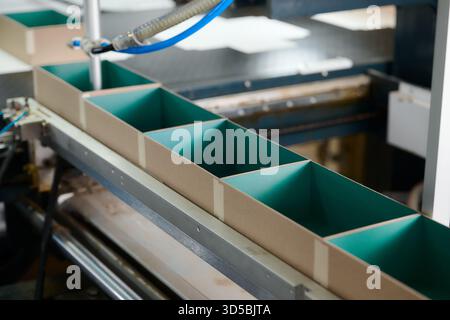 Conveyor belt transporting colorful cardboard boxes in a decorative packaging factory during the vibrant manufacturing process Stock Photo