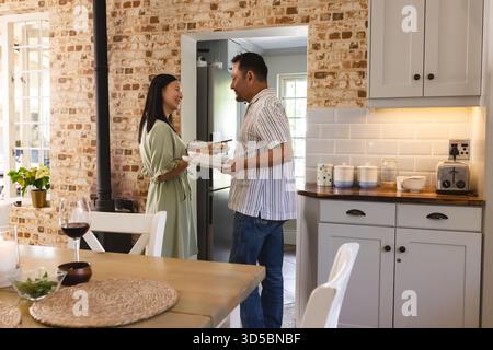 Asian couple in kitchen sharing laugh while preparing dinner together Stock Photo