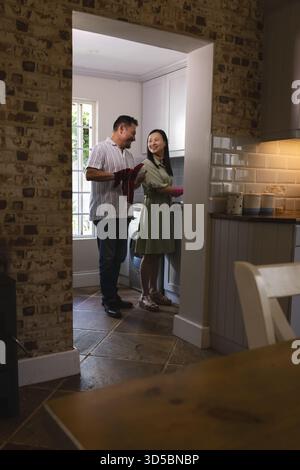 Asian couple cooking together in cozy kitchen, sharing joyful moment Stock Photo