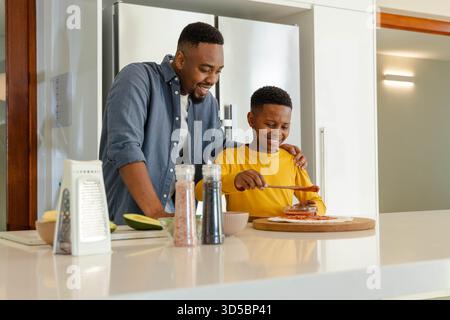 Father and son making homemade pizza together in modern kitchen, enjoying bonding Stock Photo